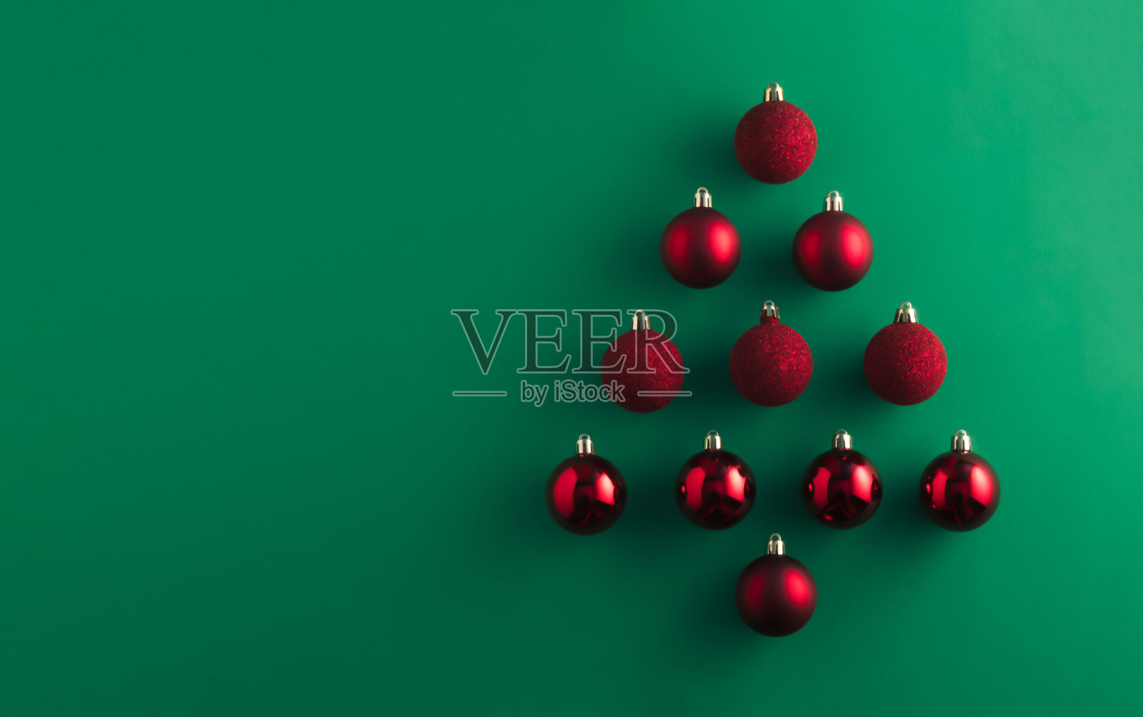 圣诞树用红色的装饰物装饰在绿色的桌子背景上。圣诞组成。平铺，俯视图。新年促销卡。副本的空间。照片摄影图片