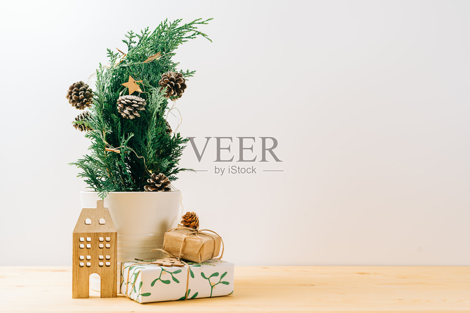 有创意的自然盆景圣诞树在木桌上与礼品盒和白色背景。圣诞贺卡与复制空间。新年快乐照片摄影图片