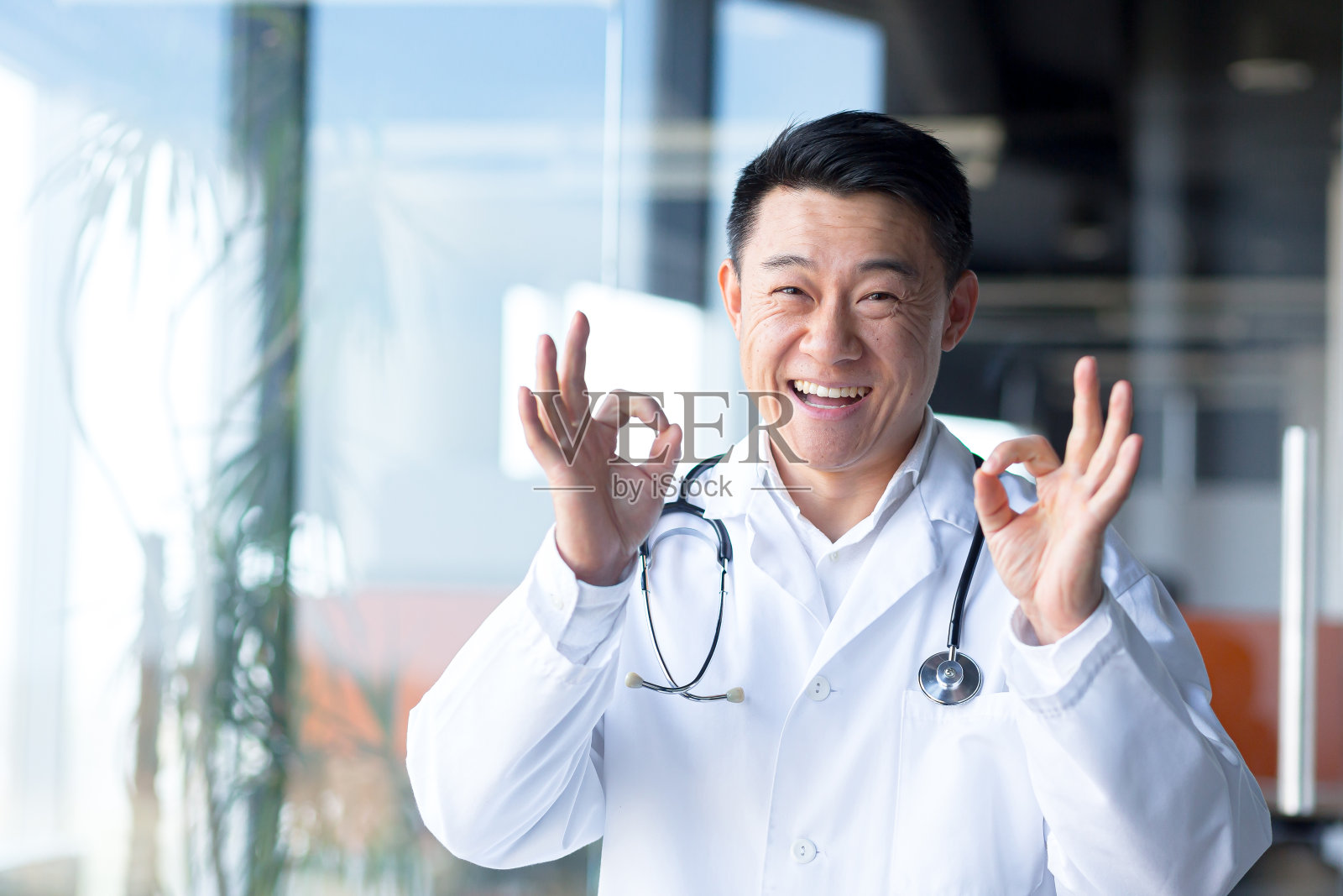 一个成功的快乐和快乐的亚洲医生的肖像，男人在现代诊所看着相机和微笑照片摄影图片