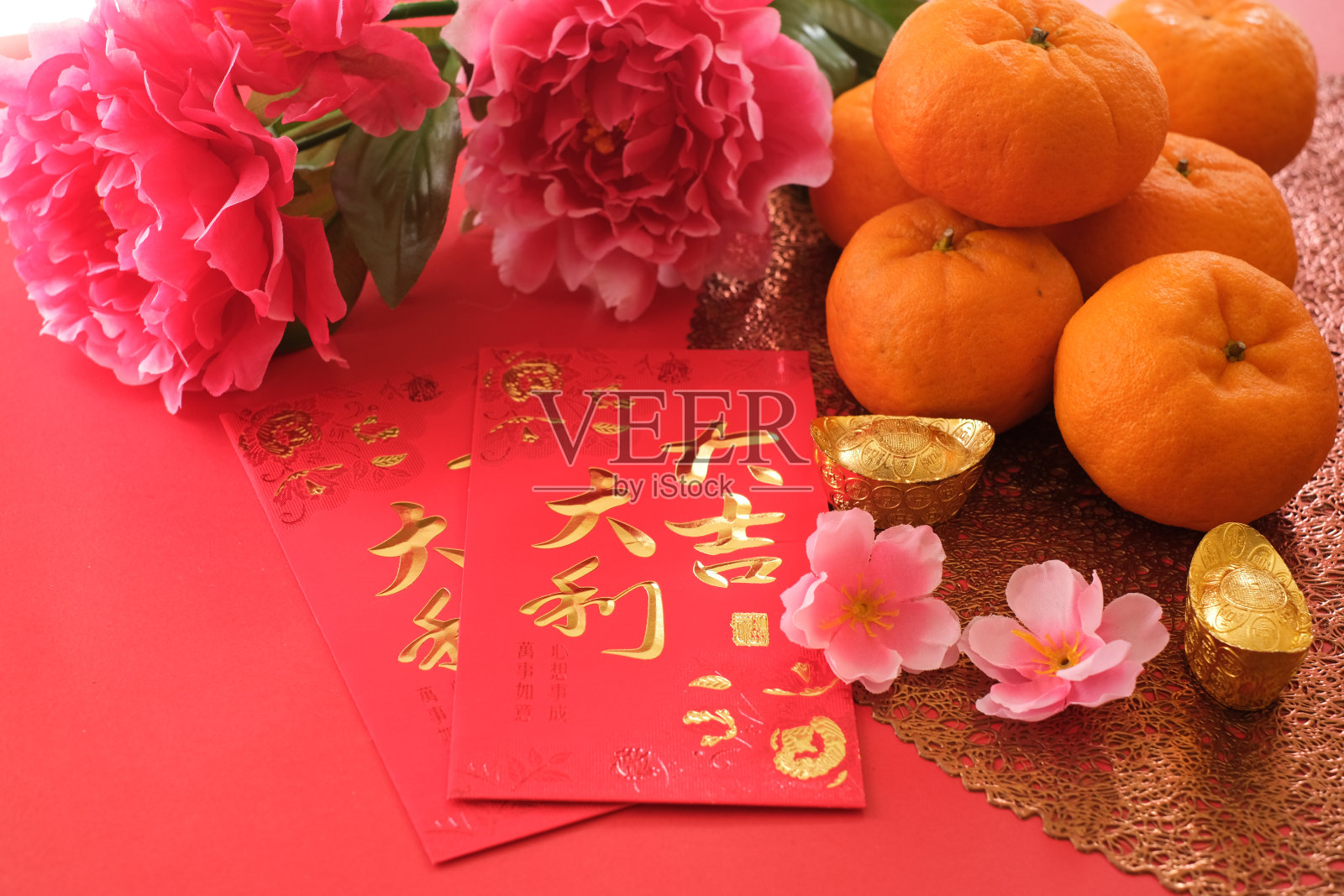 中国新年的节日概念。在红色的背景上用梅花装饰的橘子、红包和金锭。汉字“大吉大利”意为大运大利。照片摄影图片