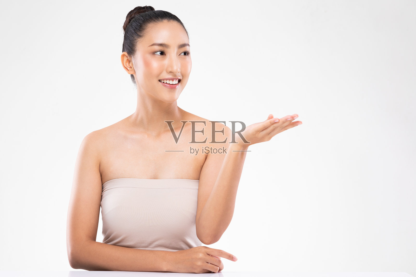 美丽迷人迷人的亚洲年轻女子微笑着洁白的牙齿张开手掌展示化妆品产品愉悦健康的皮肤，孤立在白色的背景，美容化妆品的概念照片摄影图片