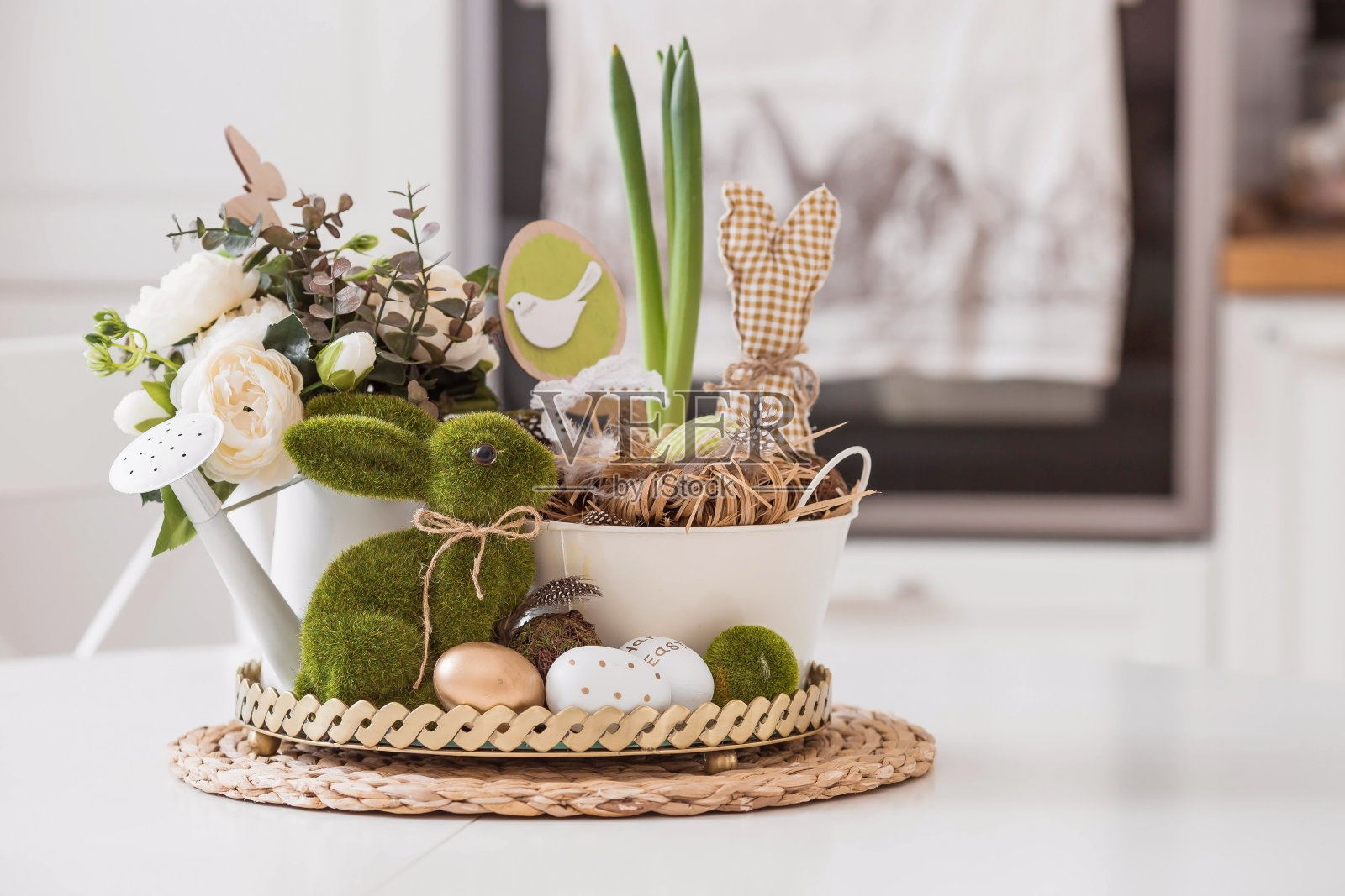 桌子上有一个铁锅，上面放着复活节彩蛋、鲜花和兔子。背景是白色的斯堪的纳维亚风格的厨房。在2022年复活节这个明亮的节日里，家居舒适和装饰的概念。照片摄影图片