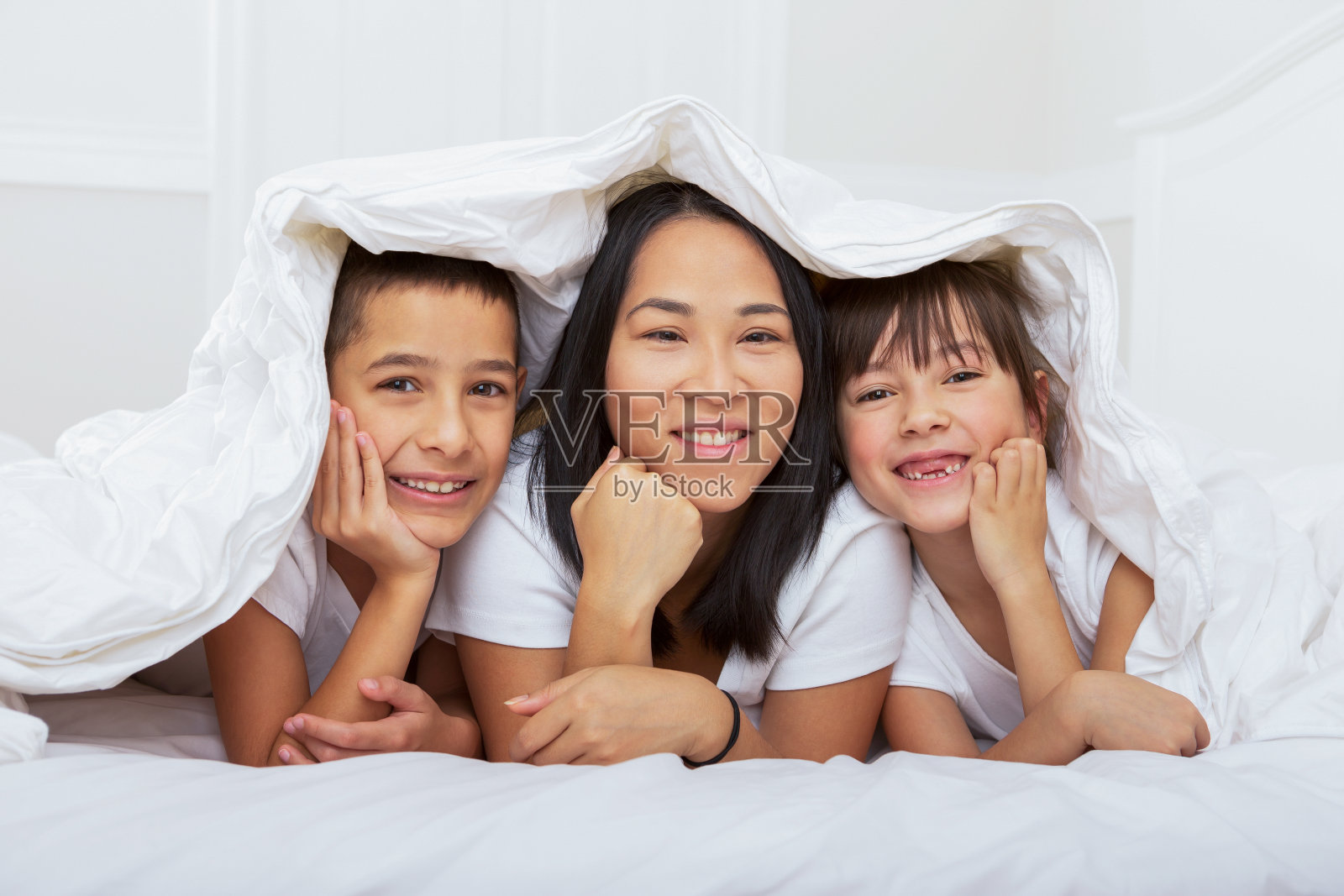 快乐的妈妈和两个孩子在床上照片摄影图片