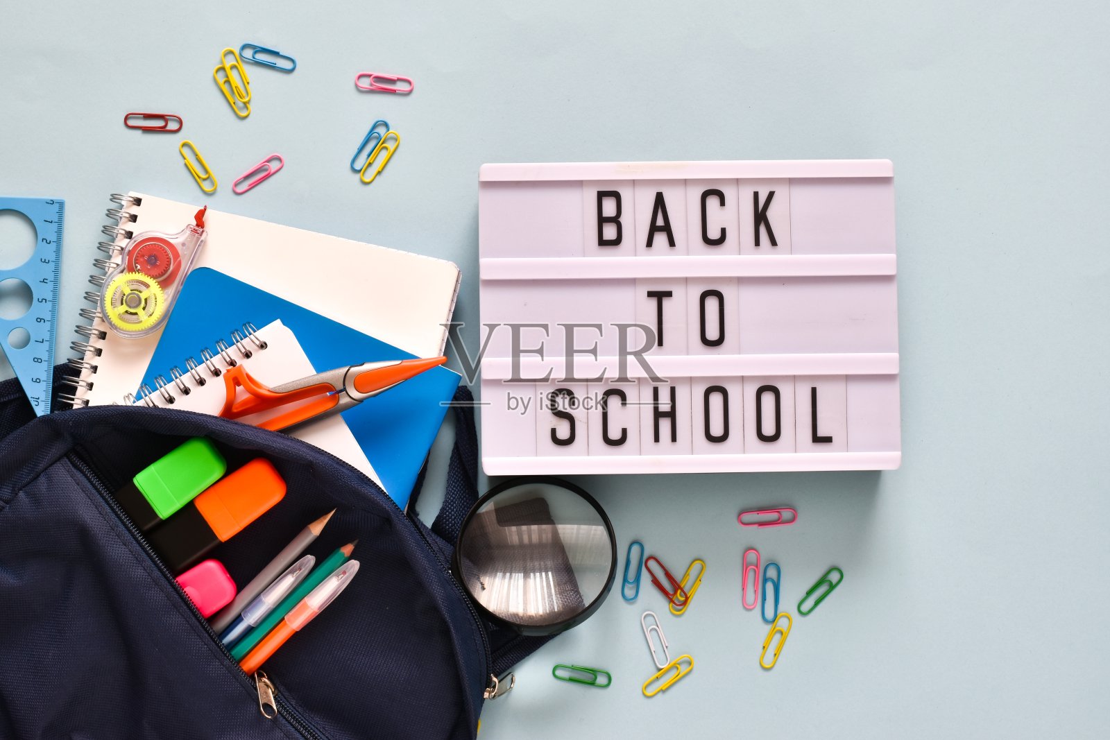 回到学校概念。Light box with text BACK TO SCHOOL和Backpack with SCHOOL supplies on Light blue背景照片摄影图片