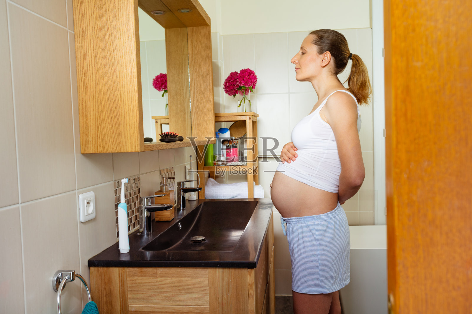 孕妇在浴室对着镜子欣赏肚子照片摄影图片