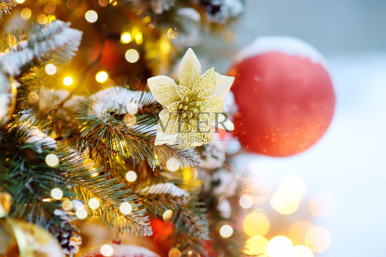 用金色、红色的球和花朵装饰的人造圣诞树树枝。特写镜头。传统城市户外圣诞市场。城市庆祝装饰照片摄影图片