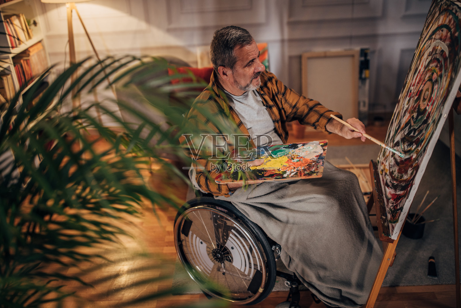一位坐在轮椅上的残疾人在工作室的画布上作画照片摄影图片