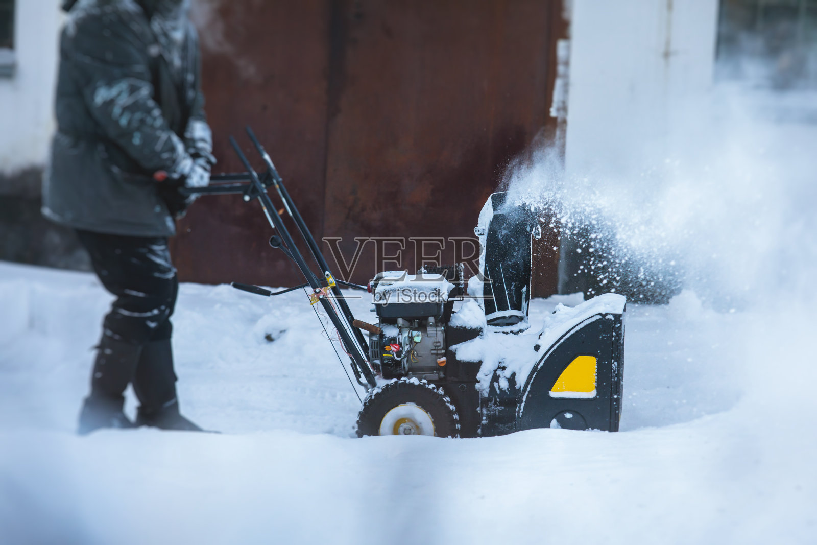 使用便携式吹雪机除雪过程，冬天工人穿着工作服在街上用气体吹雪机除雪照片摄影图片
