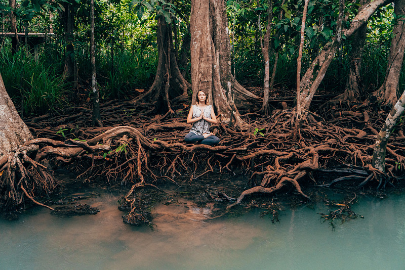 在热带森林的河边做瑜伽的女人图片下载
